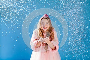 Portrait of a beautiful fashionable girl in a dress and a hat with snow in winter