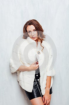 Portrait of a beautiful fashionable woman with curls in a white fur coat