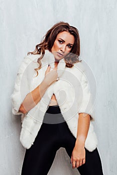 Portrait of a beautiful fashionable woman with curls in a white fur coat