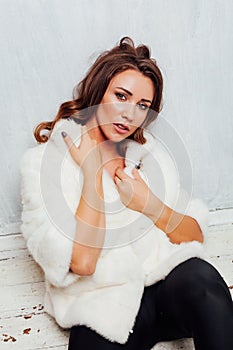 Portrait of a beautiful fashionable woman with curls in a white fur coat