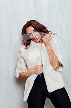 Portrait of a beautiful fashionable woman with curls in a white fur coat