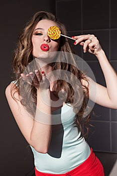 Portrait of a beautiful fashionable woman eats candy big sweet lollipop