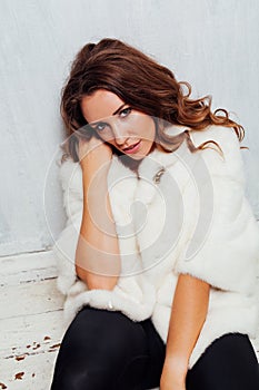 Portrait of a beautiful fashionable woman with hair curls in a white fur coat