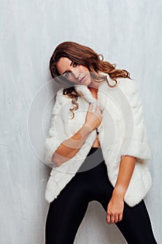 Portrait of a beautiful fashionable woman with hair curls in a white fur coat