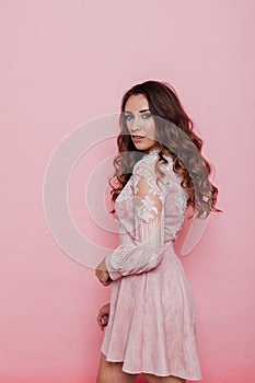 Portrait of a beautiful fashionable woman with locks in a pink dress