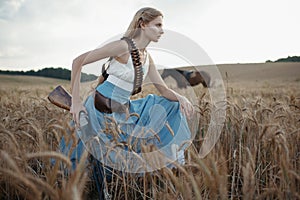 Portrait of a beautiful female cowgirl with shotgun from wild west riding a horse in the outback.