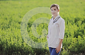 Portrait of a beautiful female doctor or nurse on green grass background