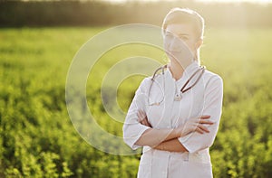 Portrait of a beautiful female doctor or nurse on green grass background