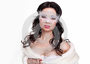 Portrait of a beautiful female model with mask in fur coat on white background