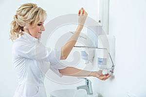 Portrait of a beautiful female surgeon doctor washing her hands preparing for surgery. Compliance with hygiene rules