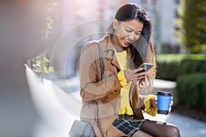Young woman with smartphone and coffee in the city photo