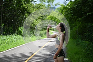 Portrait of beautiful fitness athlete woman drinking water after work out exercising.