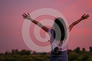 Portrait of beautiful freedom asian woman with holding medium format film camera with colorful sunset sky background