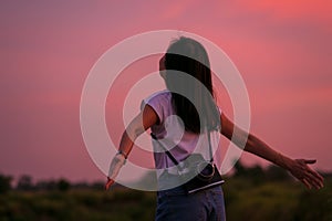 Portrait of beautiful freedom asian woman with holding medium format film camera with colorful sunset sky background