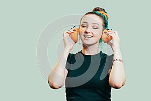 Portrait of beautiful funny girl with orange halves like headphones for listening to music, woman fooling around, concept music of