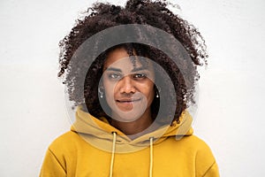 Portrait of beautiful girl with afro hairstyle looking at the camera, posing on the white wall. Natural beauty