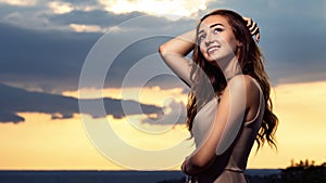 Portrait of a beautiful girl against the background of a cloudy evening sky at sunset, a young woman in a summer dress resting on
