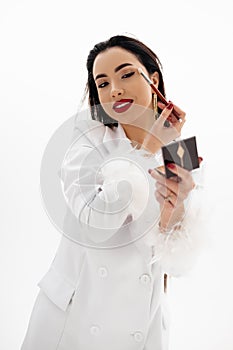 Portrait of a beautiful girl applying a makeup on a white background