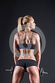 Portrait of a beautiful girl athlete with a dumbbell in studio