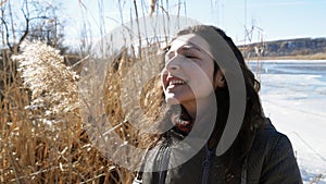 Portrait of a beautiful girl on the bank of a frozen river enjoying nature, laughing and playing with yellow cane