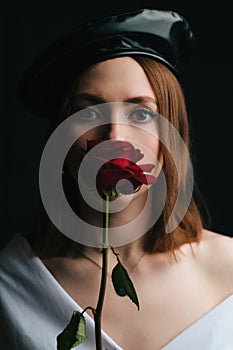 Portrait of a beautiful girl in a black beret. A young girl in the studio in the image of a Parisian woman with a red