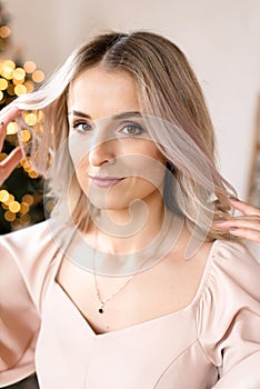 Portrait of a beautiful girl with blond hair against a festive light garlands