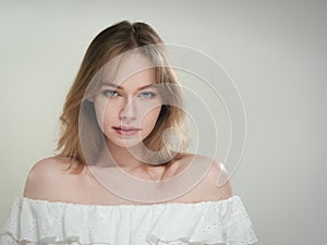 portrait of a beautiful girl with blue eyes on a gray background in the studio