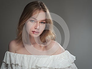 portrait of a beautiful girl with blue eyes on a gray background in the studio
