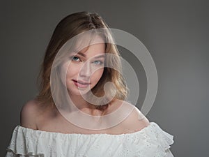 portrait of a beautiful girl with blue eyes on a gray background in the studio