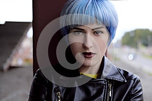 Portrait of beautiful girl with blue hair and red lips in a yellow sweater at the construction site