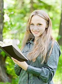 Portrait of beautiful girl with book in park