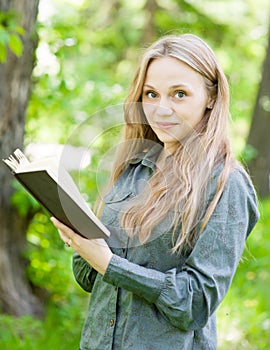 Portrait of beautiful girl with book in park