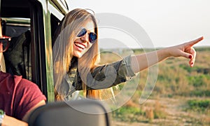 Portrait of beautiful girl on car roadtrip pointing forward.