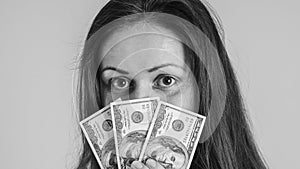 Portrait of a beautiful girl covering her face with dollar bills. Black and white photo