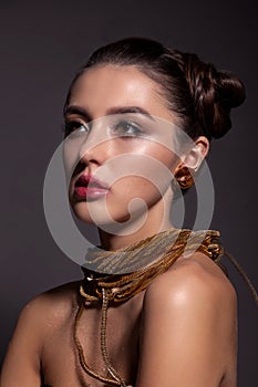 Portrait of a beautiful girl with a creative hairstyle and makeup on a gray background.