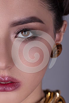 Portrait of a beautiful girl with a creative hairstyle and makeup on a gray background.