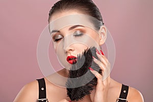 Portrait of a beautiful girl with dark hair, with beautiful makeup, red lipstick and healthy clean skin. She is holding a black