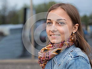 Portrait of a beautiful girl in a denim jacket with a scarf