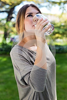 Portrait of beautiful girl drinking water glass at green park.