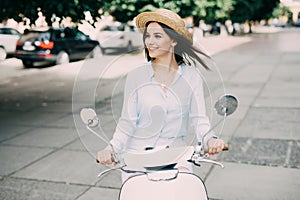 Portrait of a beautiful girl drive on retro scooter, smiling and looking at the camera