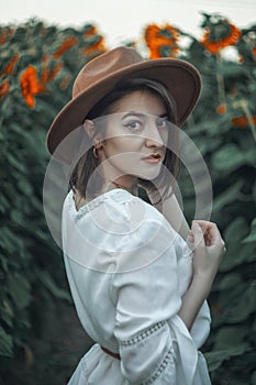 Portrait of a beautiful girl in a field of sunflowers. Warm summer shot of a girl in the field