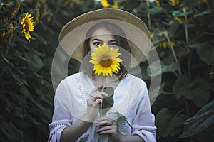Portrait of a beautiful girl in a field of sunflowers. Warm summer shot of a girl in the field
