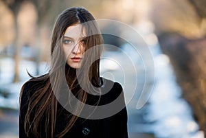 Portrait of a beautiful girl with flying hair in the wind. Young sad woman. Portrait of lonely woman