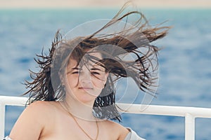 Portrait of a beautiful girl with freckles, the wind develops hair on a background of blue sea