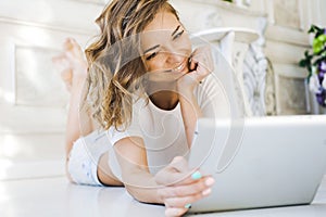 Portrait of a beautiful girl gentle, cute young, lying on the floor, with laptop posing