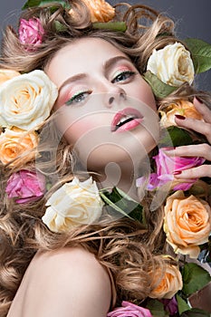 Portrait of a beautiful girl with a gentle pink make-up and lots of flowers in her hair. Beauty face.