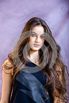 Portrait of a beautiful girl on a gray background, in a black dress with a serious look with perfect makeup isolated on black back