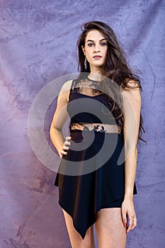 Portrait of a beautiful girl on a gray background, in a black dress with a serious look with perfect makeup isolated on black back