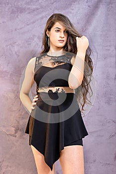 Portrait of a beautiful girl on a gray background, in a black dress with a serious look with perfect makeup isolated on black back