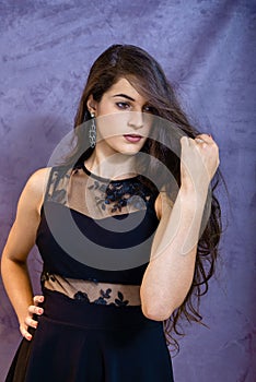 Portrait of a beautiful girl on a gray background, in a black dress with a serious look with perfect makeup isolated on black back
